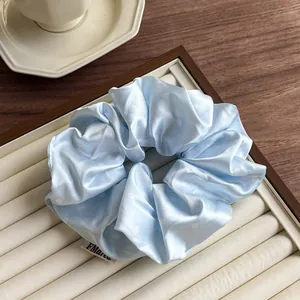 Detail showing a light blue satin scrunchie with white polka dots on a display tray
