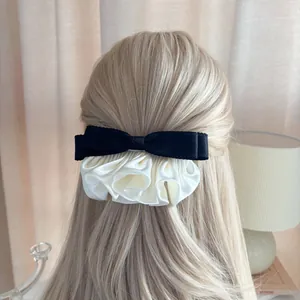 Barrette à cheveux élégante en satin crème et noir avec bords ondulés sur mannequin