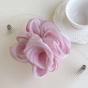 Close-up of pink oversized pearlescent silk scrunchie on a textured glass tray