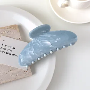 Detail of light blue marble textured large hair claw clip on an aesthetic tray