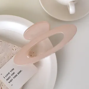 Detail view of large nude pink oval claw clip on elegant ceramic tray with soft lighting