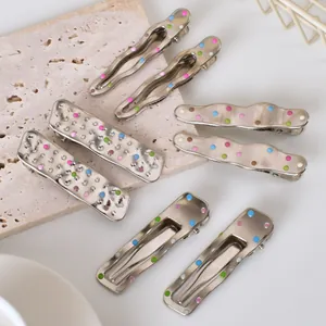 Detailed close-up of 8-piece silver metal hair clips with colorful polka dots on stone base