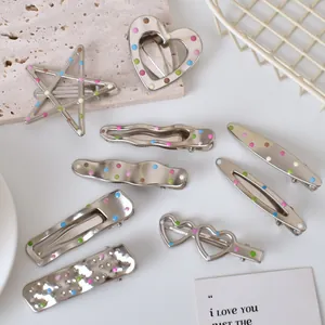 Detailed macro of silver metal hair clips with colorful polka dots on a stone background