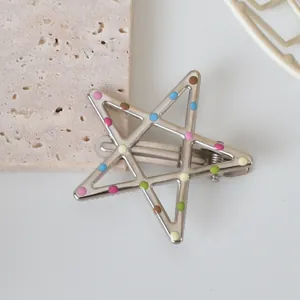 Detail of silver star hair clip with colorful polka dots on a textured stone