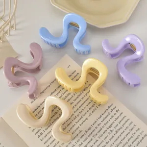 Détail de cinq pinces à cheveux ondulées en résine colorée sur un livre ouvert