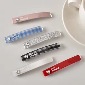Détail de barrettes à carreaux avec strass en forme de cœur et texte lar mood