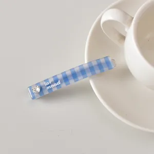 Détail d'une barrette à carreaux bleus avec strass en cœur et lettrage sur la table