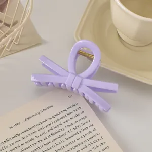 Détail d'une pince à cheveux nœud lavande avec ressort doré posée sur un livre