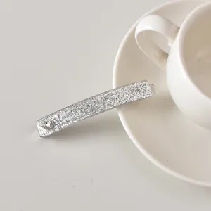 Détail d'une barrette argentée scintillante avec strass en cœur et imprimé low mood