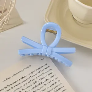 Détail de la pince à cheveux nœud bleu clair sur livre avec un design minimaliste