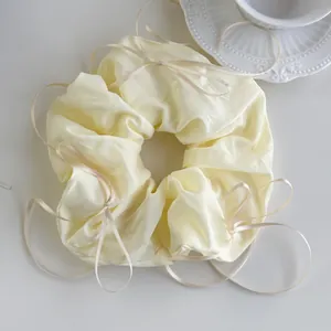 Detailed view of cream-colored oversized scrunchie with elegant flowing satin ribbons