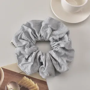 Detail of light blue scrunchie with white flower embroidery and small FMdre woven label