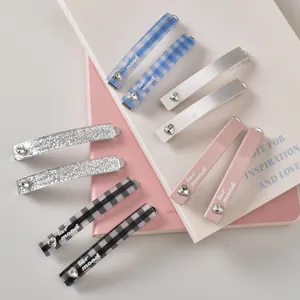 Détail de barrettes à carreaux bleus avec strass en cœur et logo lar mood