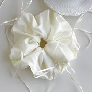 Detail of cream white oversized scrunchie with romantic ribbon ties and pleated texture