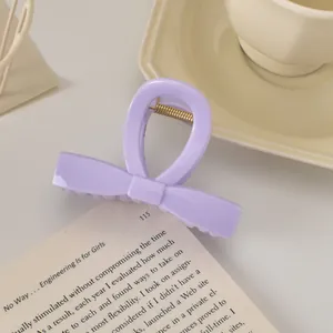 Détail d'une pince à cheveux nœud lavande avec ressort doré sur un livre ouvert