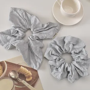 Detailed close-up of light blue scrunchies featuring delicate floral embroidery and brand tags