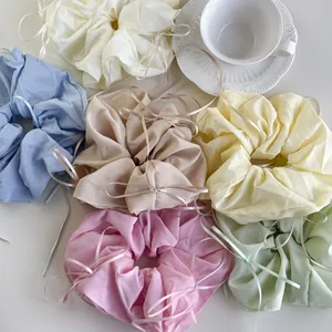 Detail of six colorful oversized silk scrunchies with ribbons in soft pastel tones
