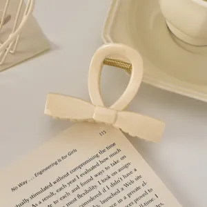 Détail d'une pince à cheveux nœud crème posée sur un livre pour un style élégant