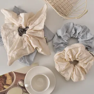 Floral embroidery hair scrunchies in cream and blue on a cozy lifestyle background