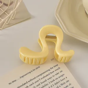 Détail d'une pince à cheveux jaune crème ondulée avec finition brillante et ressort doré