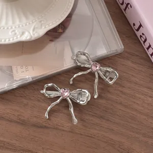 Silver liquid metal bow hair clips with pink heart crystal on a decorative ceramic plate
