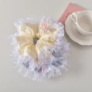Détail du chouchou en dentelle rayé jaune et bleu avec nœud rose et étiquette