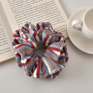 Macro detail of a striped knit scrunchie with red, navy and white texture on a book