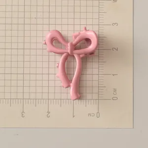 Dettaglio della mini pinza per capelli rosa a fiocco con finitura laccata lucida