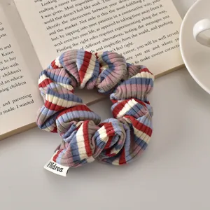 Detailed texture of blue and red striped knit scrunchie with FMdrea woven label