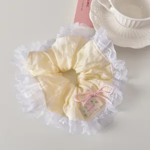 Détail du chouchou rayé avec bordure en dentelle, nœud rose et étiquette fait main