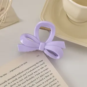 Gros plan sur la pince à cheveux lavande en forme de nœud posée sur un livre ouvert