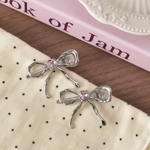 Silver liquid metal bow hair clips with pink heart rhinestones on polka dot fabric