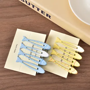 Dettaglio di fermagli per capelli a forma di pesce blu e crema su carta fatta a mano