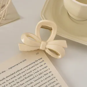 Détail d'une pince à cheveux nœud crème montrant la texture mate et le ressort en métal