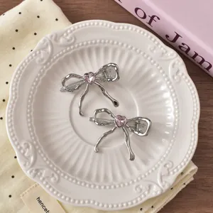 Detail of silver bow hair clips with pink heart crystals on a vintage ceramic plate