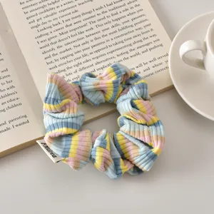 Detail of blue striped scrunchie with Andrea label on an open book in a cozy setting