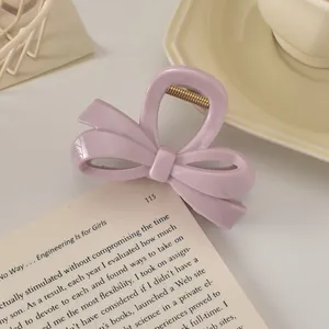 Gros plan d'une pince à cheveux nœud lilas avec ressort doré sur un livre ouvert