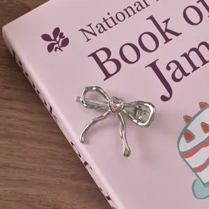 Detail of silver bow hair clip with pink heart rhinestone on a decorative book