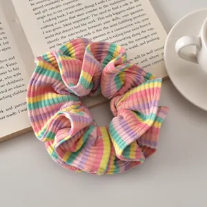 Close-up of pastel striped scrunchie on a book with a coffee cup for a cozy vibe