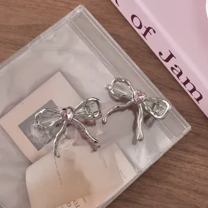 Detailed view of silver bow hair clips with pink heart rhinestones on a decorative desk