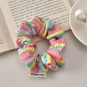 Macro view of blue striped hair scrunchie with colorful rainbow pattern and fabric label
