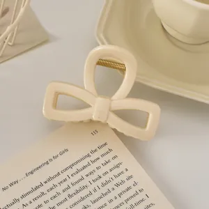 Vue détaillée de la pince à cheveux nœud crème sur un livre, design élégant en résine