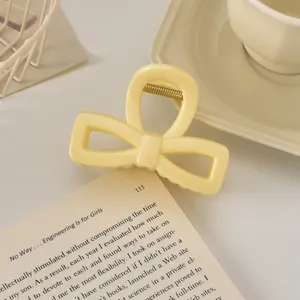 Détail de la pince à cheveux nœud jaune crème montrant la texture résine et le ressort