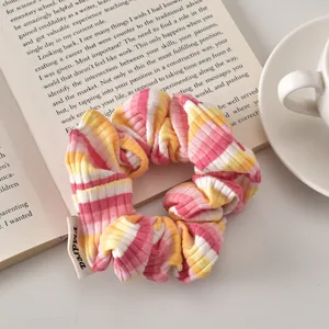 Detail view of pink and yellow striped fabric scrunchie resting on an open book