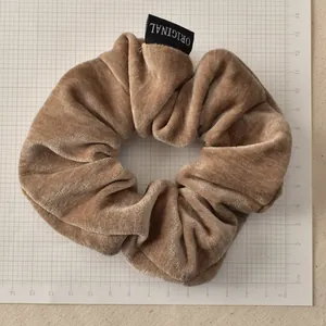 Close-up of caramel velvet scrunchie showing soft texture and original woven label