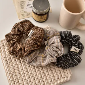 Trois chouchous à carreaux en laine marron et gris sur un tapis tissé élégant