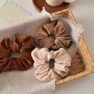 Three-piece velvet hair scrunchies set in brown tones displayed in a woven basket