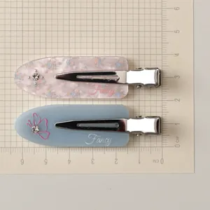 Detail of two acrylic hair clips with floral and butterfly patterns, sized 6cm long