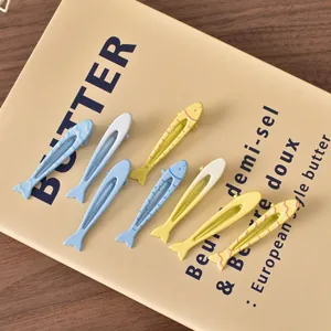 Fermagli per capelli a forma di pesce color pastello disposti su un tavolo di legno rustico