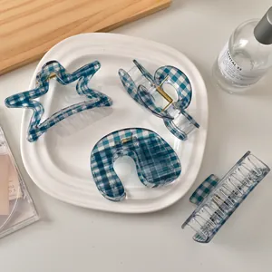 Detailansicht von vier blauen Gingham-Resin-Haarklammern mit goldenen Metallfedern